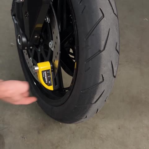 The yellow LoudLock clamped on a motorcycle’s front brake disc